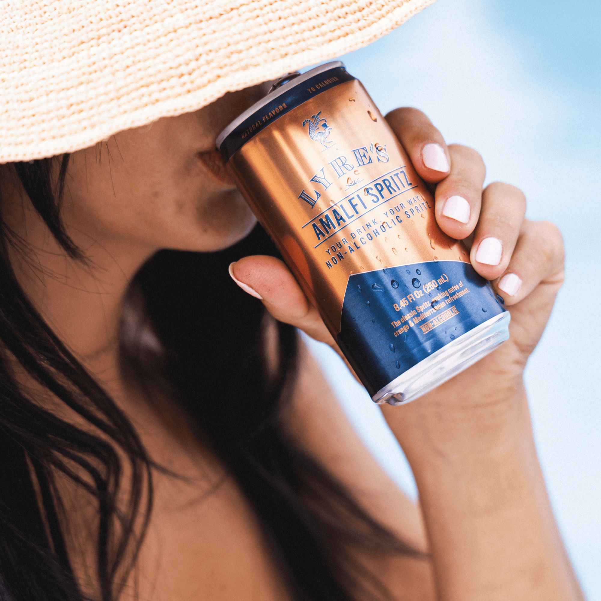 Person holding a can of Lyre's Amalfi Spritz non alcoholic cocktail against a blurred background