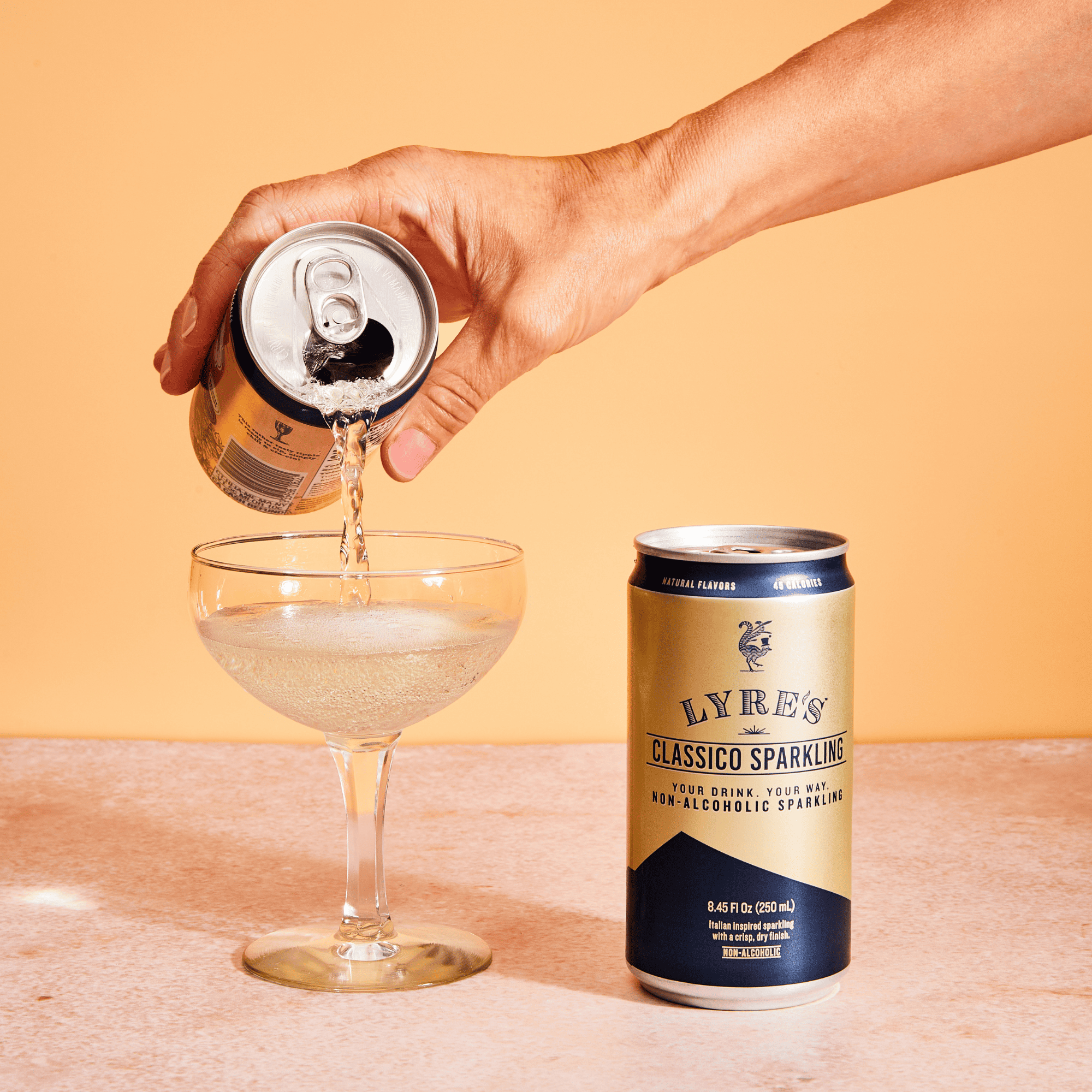 Hand pouring Lyre's Classic Sparkling into a glass with a can of the non alcoholic sparkling wine alternative.