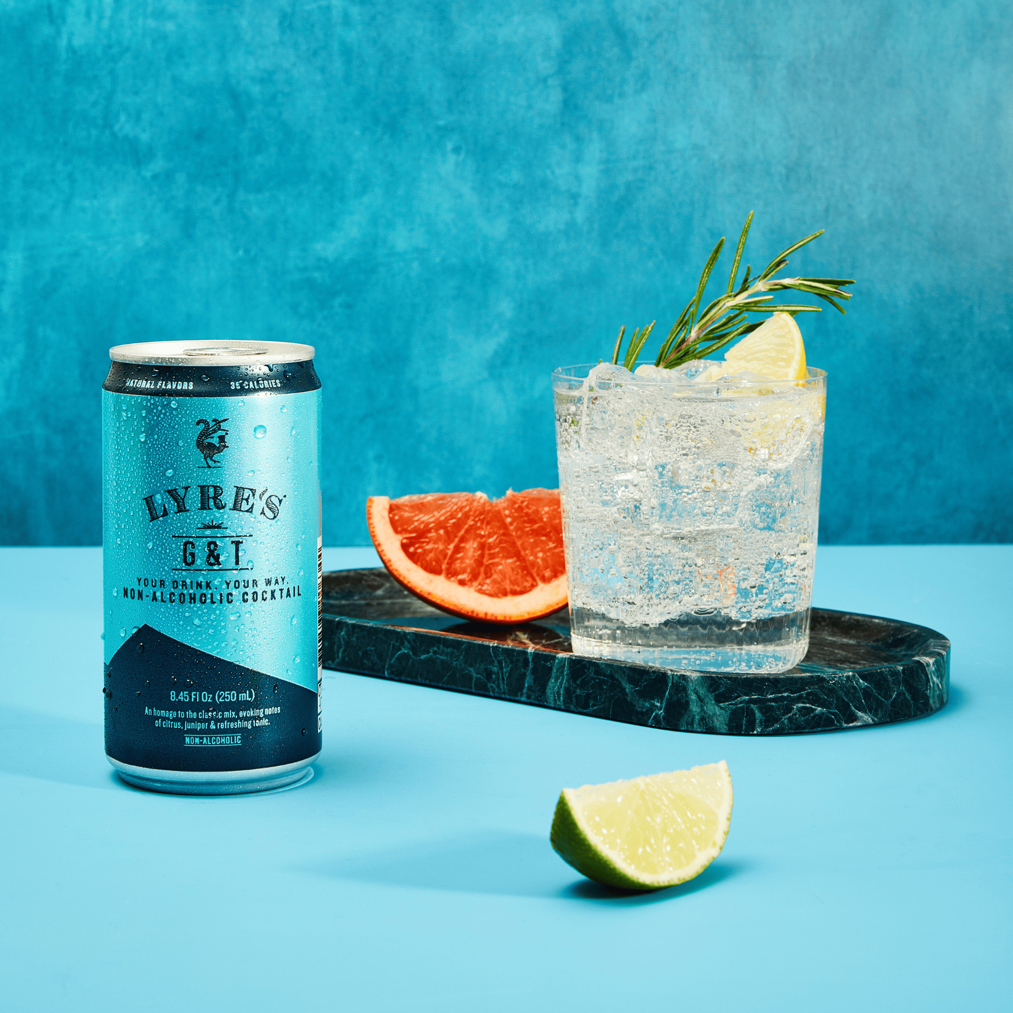 Lyre's non-alcoholic cocktail can with a glass of Non alcoholic gin and tonic on a blue background
