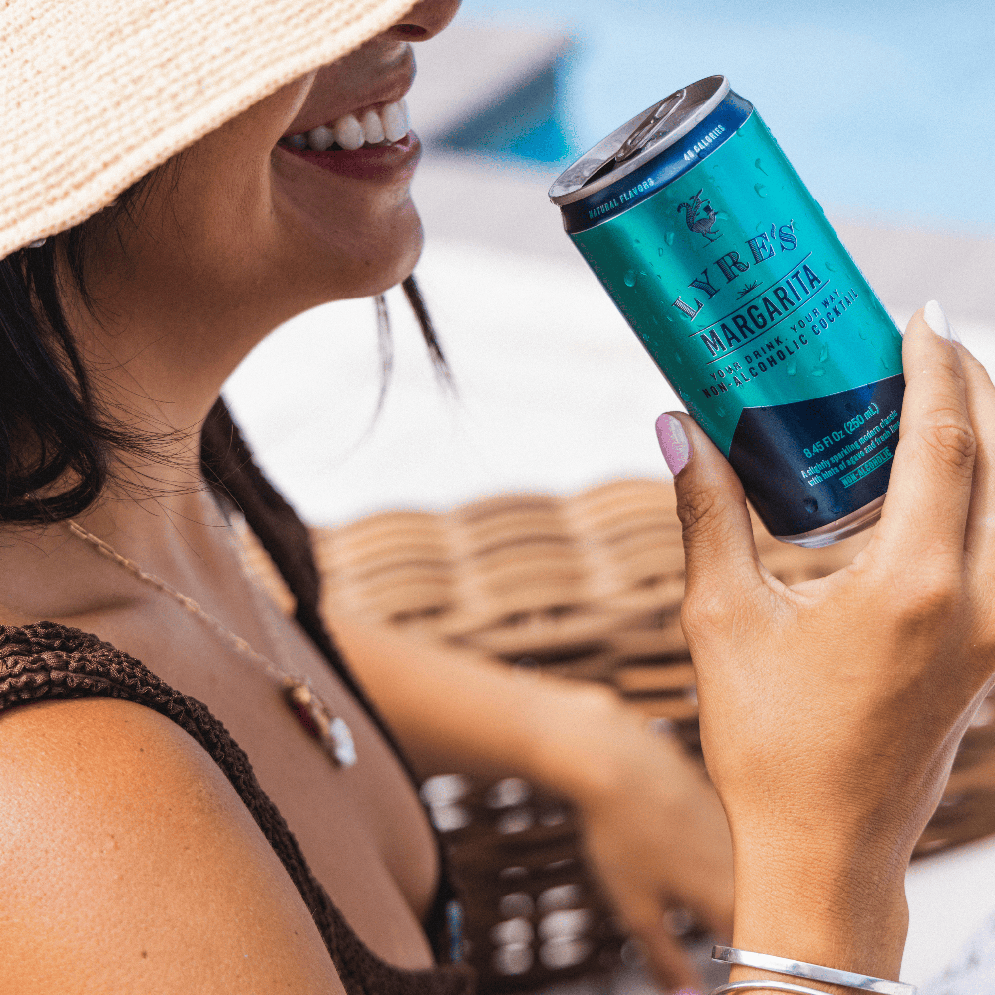 Woman holding a can of Lyre's Margarita non alcoholic cocktail with a blurred outdoor background