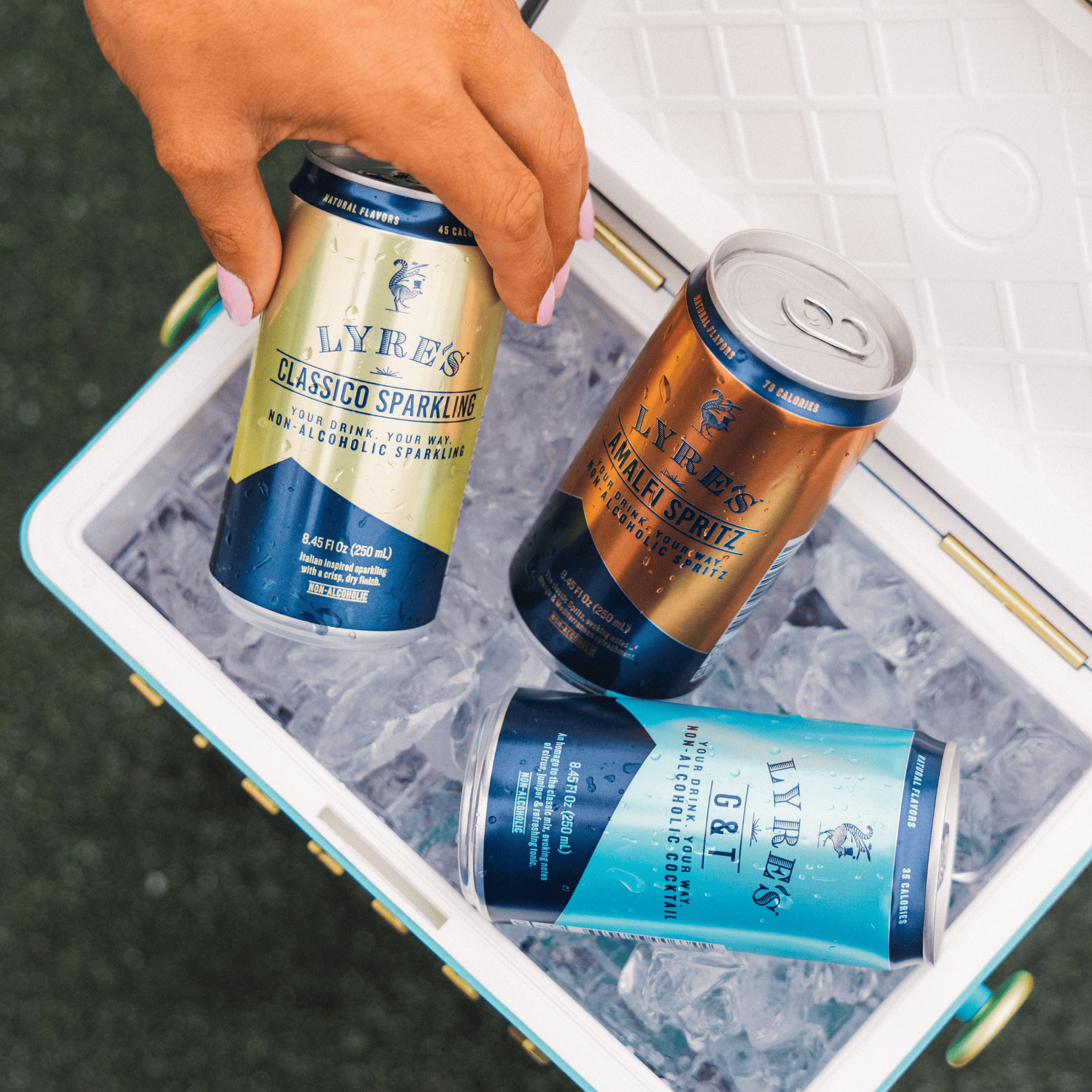 Hand reaching into a cooler with Lyres ready to drink non alcoholic cocktails in a can on ice.