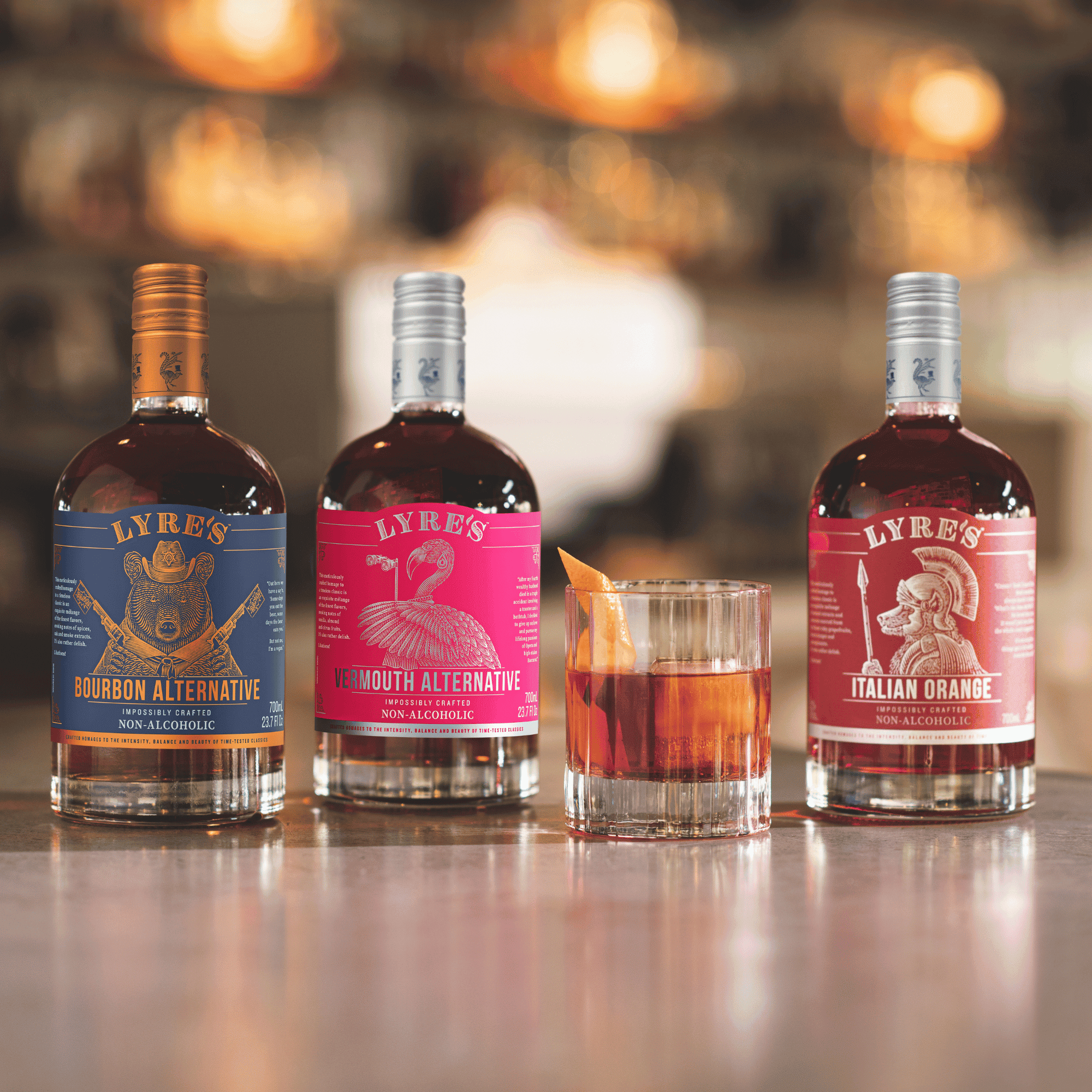 Lyre's Bourbon Alternative, Vermouth Alternative and Italian Orange alcohol free alternatives on a bar with a mocktail.