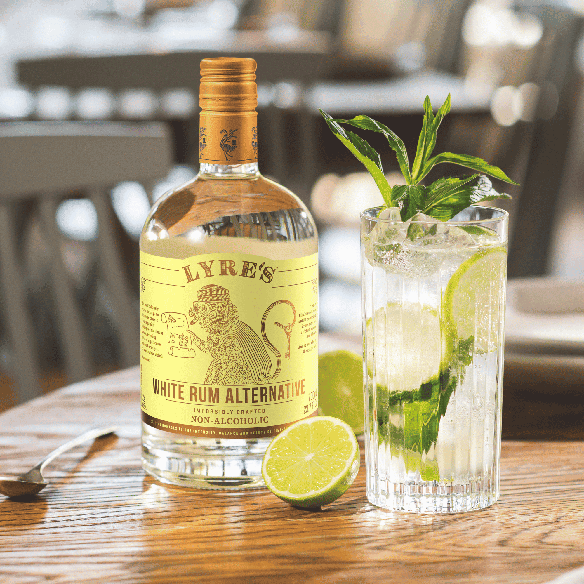 Lyre's White Rum Alternative bottle with an alcohol free mojito on a wooden table outdoors.